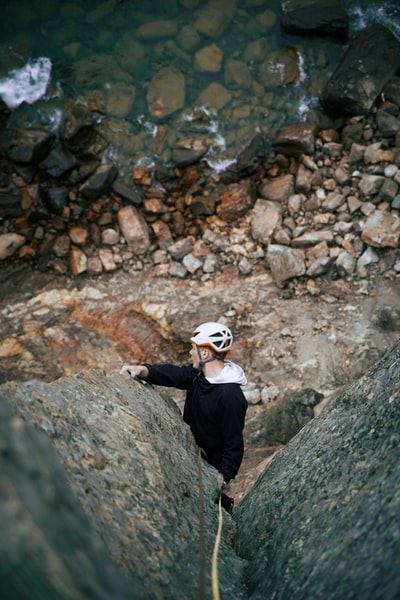 黑色上衣和白色帽的男人站在岩石地面
